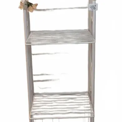 Tall white painted wrought iron baker's rack featuring decorative scrolled top detail, slatted shelves, and artificial floral accents.