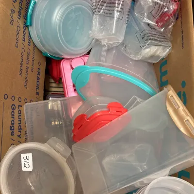 Cardboard box filled with assorted plastic food storage containers and snap-locking lids.