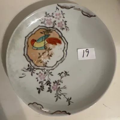 Vintage Japanese porcelain decorative plate featuring a hand-painted bird in a central medallion and cherry blossom floral accents.
