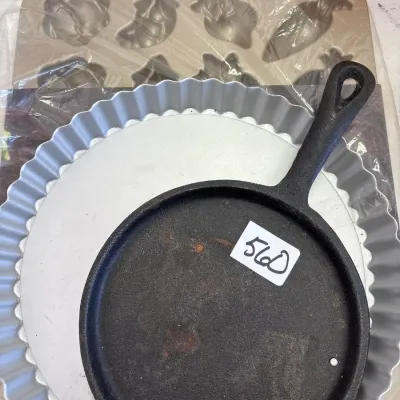 Collection of assorted bakeware and cookware including a small cast iron skillet, a fluted aluminum tart pan, and a vegetable-shaped mold...