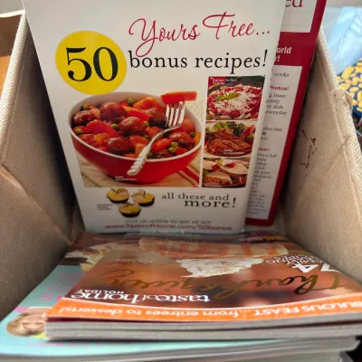 Collection of modern Taste of Home cooking magazines and recipe booklets stored inside a fabric bin.