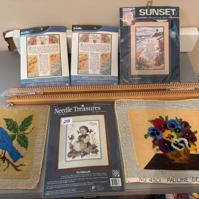 Collection of vintage needlecraft kits and completed needlepoint canvases, including Bucilla and Sunset cross stitch kits, alongside a...
