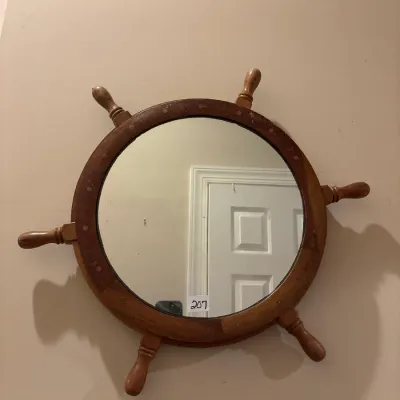 Vintage nautical ship wheel wall mirror in a wooden frame with spoke handles.