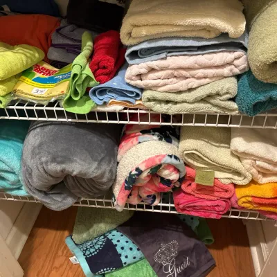 Assortment of folded bath towels, hand towels, and fleece blankets organized on wire closet shelving.