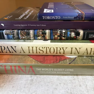 Stack of hardbound and softcover books on art, history, and language, including 'Japan: A History in Art' and 'China: The...