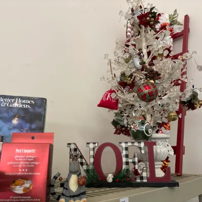 Collection of holiday decorations including a small embellished faux tabletop tree, a buffalo-plaid "NOEL" sign, a cat...