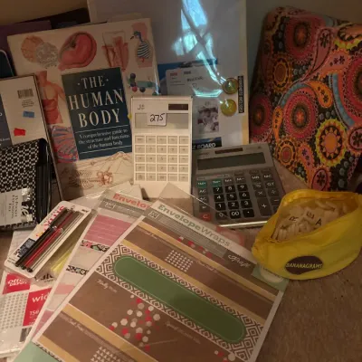 Assortment of office and craft supplies including calculators, stationery, a dry-erase board, "The Human Body" book, and a...