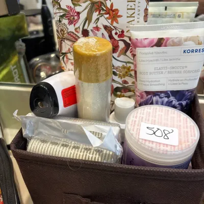 Brown fabric storage bin filled with various bath and body products, including Korres body butter and a floral Bakery Beauty gift box.