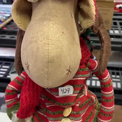 Whimsical plush Christmas moose figure dressed in a striped sweater, red hat, and scarf, showing light surface wear.