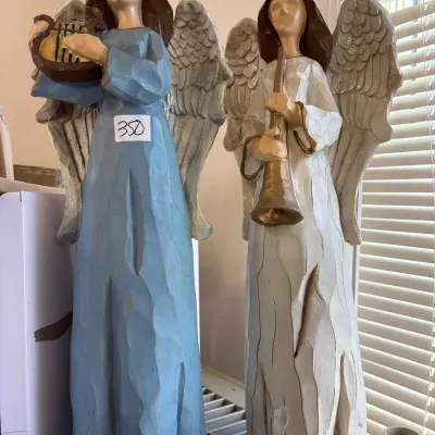 Pair of carved wood-look resin angel figurines holding musical instruments, featuring faceted textures and glittery wings.
