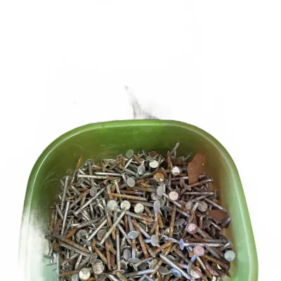 Assorted vintage roofing nails with flat heads and varying surface rust, stored in a green plastic container.