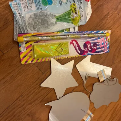 Collection of craft and novelty items including a folding vase kit, a ribbon twirler wand, and various wooden hanging signs.