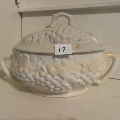 Vintage white ceramic tureen with lid, featuring an embossed grape and vine motif and dual side handles.
