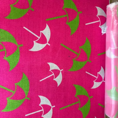 Vibrant hot pink area rug featuring a repeat pattern of green and white umbrellas, shown flat alongside another rolled rug in plastic wrap.