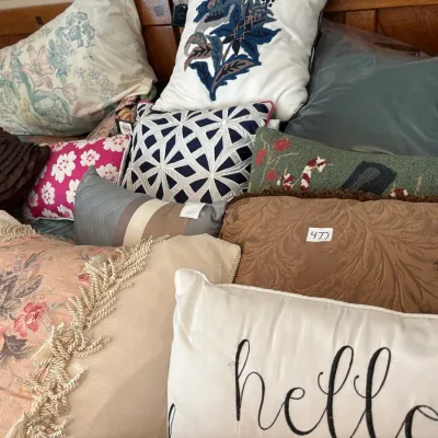 An assortment of decorative throw pillows in various patterns, fabrics, and colors arranged on a bed.