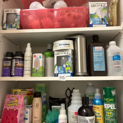 Shelves filled with various household supplies, including light bulbs, cleaning products, personal care items, and bug sprays.