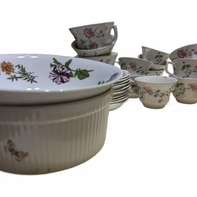 Collection of floral porcelain tableware, including a fluted souffle dish, serving bowls, small saucers, and teacups with botanical motifs.