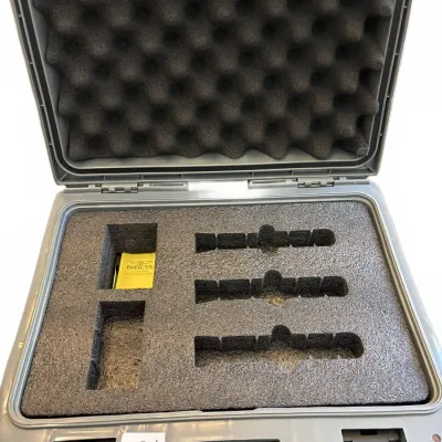 Open grey hard-shell carrying case with custom foam cutouts, featuring an Invicta instruction booklet inside.