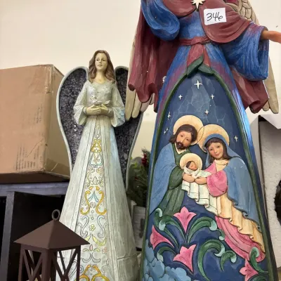 Two resin angel figurines, including a Jim Shore Heartwood Creek style nativity angel and a silver-and-white angel holding a bird,...
