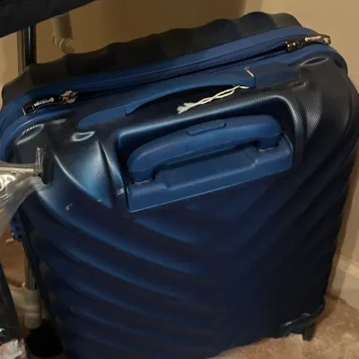 Blue hardshell spinner suitcase by Rockland, featuring a textured chevron pattern and a telescoping handle.