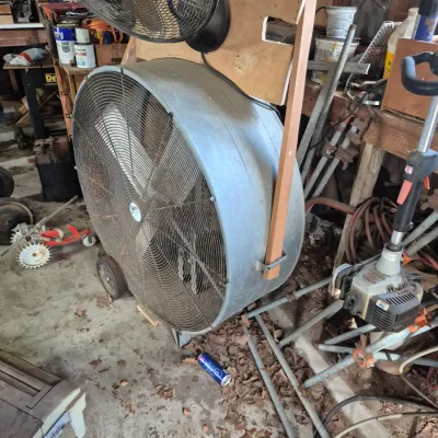 Sale Photo Thumbnail #95: Large industrial metal drum fan mounted on wheels, with a smaller portable fan attached to the frame above.