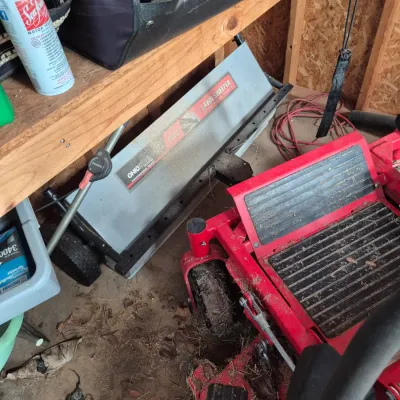 Sale Photo Thumbnail #114: Ohio Steel tow-behind lawn sweeper stored in a shed alongside a red riding lawn mower and outdoor supplies.