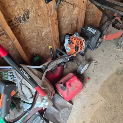 Sale Photo Thumbnail #109: Stihl gas-powered yard tiller and additional outdoor lawn equipment stored in a shed.
