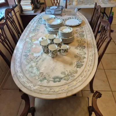 Sale Photo Thumbnail #46: Oval dining table with a painted top and six carved wooden chairs, set with a matching leaf-pattern porcelain dinnerware set.