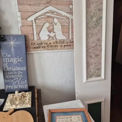 Sale Photo Thumbnail #20: Collection of holiday decor and artwork, including a rustic nativity scene wall hanging, a painted wooden Christmas sign, and framed pictures.
