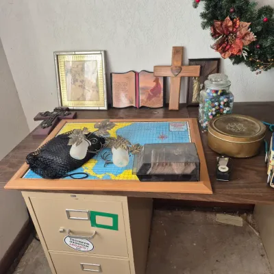 Sale Photo Thumbnail #22: Collection of home decor, religious items, glass marbles, and a framed map sitting atop a beige metal two-drawer filing cabinet desk.