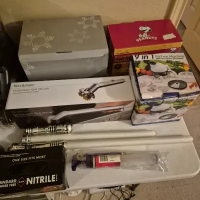 Sale Photo Thumbnail #66: Collection of boxed household items including a Brookstone motorized grill brush, 9-in-1 kitchen machine, Peanuts hot dog toaster, toy light sabers, and nitrile gloves.