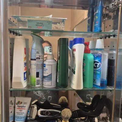 Sale Photo Thumbnail #78: Open wall-mounted mirrored medicine cabinet filled with personal care items, toiletries, electric shavers, and grooming accessories.