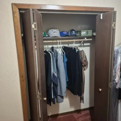 Sale Photo Thumbnail #37: Closet full of men's and women's clothing items, including jackets, pants, baseball caps, and a poncho.