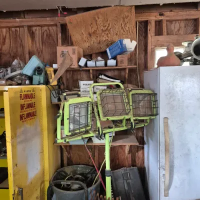 Sale Photo Thumbnail #101: Yellow triple-head portable halogen work light on a stand, surrounded by garage and shop items including a flammable safety cabinet and a white refrigerator.