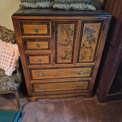 Sale Photo Thumbnail #29: Asian-inspired wooden chest of drawers featuring decorative carved and painted cabinet doors, brass hardware, and multiple storage drawers.