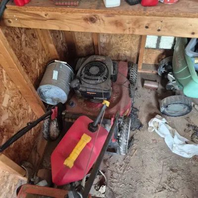 Sale Photo Thumbnail #111: Vintage Toro gas lawn mower stored in a wooden shed alongside garden supplies and equipment.