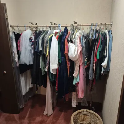 Sale Photo Thumbnail #36: Closet rack filled with a variety of men's and women's clothing, including shirts, dresses, and costumes, accompanied by wicker laundry baskets below.