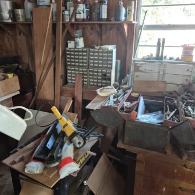 Sale Photo Thumbnail #104: Workshop area filled with various hand tools, power tools including a yellow DeWalt tool, small parts storage drawers, and assorted supplies.