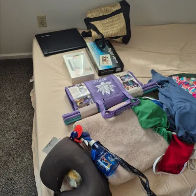 Sale Photo Thumbnail #79: Collection of miscellaneous household items including electronics, travel accessories, towels, and clothing arranged on a bed mattress.