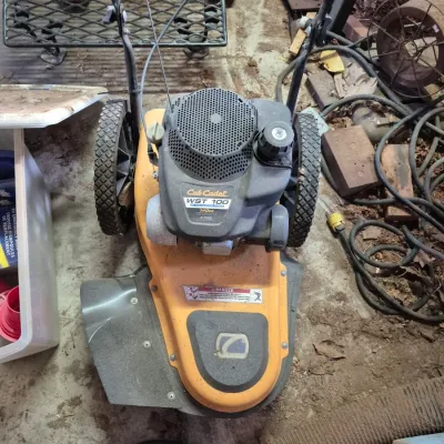 Sale Photo Thumbnail #98: Cub Cadet WST 100 walk-behind wheeled string trimmer featuring a 140cc gas engine, yellow housing, and heavy-duty treaded tires.