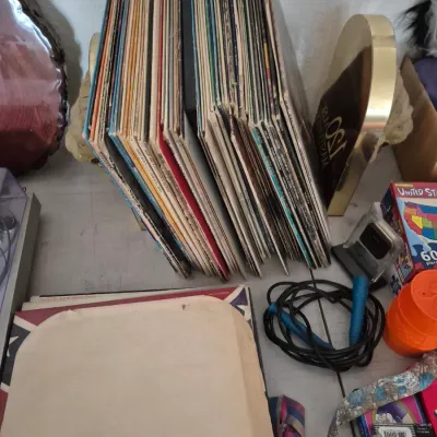 Sale Photo Thumbnail #42: Collection of vintage vinyl LP record albums held upright by brass bookends on a tabletop with various household items.