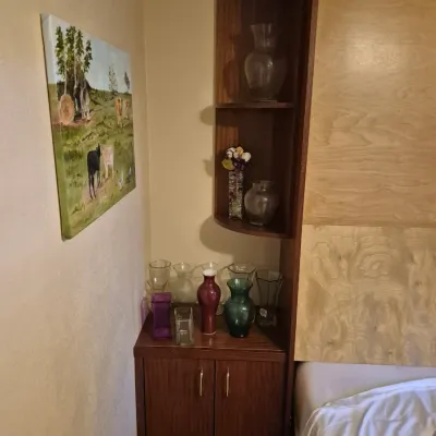 Sale Photo Thumbnail #62: Dark wood Murphy bed side cabinet unit featuring open curved upper shelving, a small lower two-door storage cabinet, and a collection of assorted glass vases.