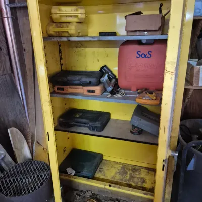 Sale Photo Thumbnail #102: Tall yellow metal tool storage cabinet filled with various power tools, blow-molded carrying cases, and a red Paslode Impulse nailer case.