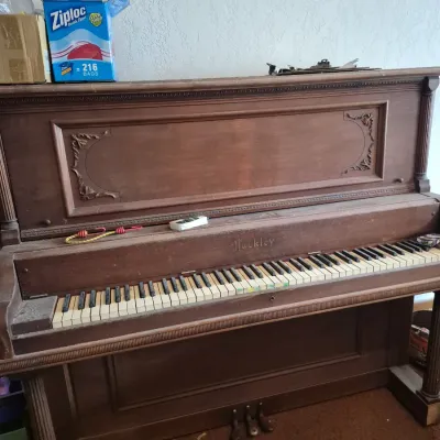 Sale Photo Thumbnail #24: Vintage Hackley upright wooden piano featuring carved detail panels and visible cosmetic wear.