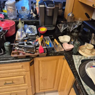 Sale Photo Thumbnail #55: Kitchen counter filled with various housewares, including a Keurig coffee maker, glassware, heart-shaped bowls, utensils, and a red Dutch oven.