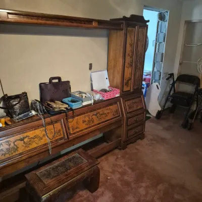 Sale Photo Thumbnail #35: Large Asian-style carved wooden wall unit vanity desk with decorative door panels, accompanied by a matching glass-top footstool and various small accessories.