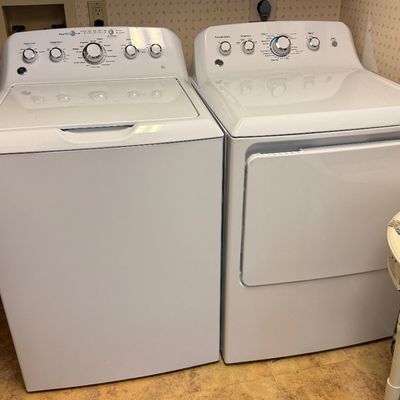 Matching white GE top-load washing machine and electric dryer set with top dial controls.