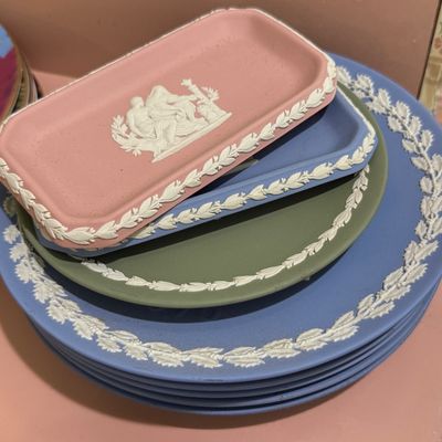 Stack of vintage Wedgwood Jasperware pieces including blue plates, a sage green tray, and a pink pin tray with white classical relief...