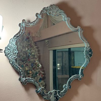 Vintage Venetian-style wall mirror with etched floral detailing along the contoured glass frame.