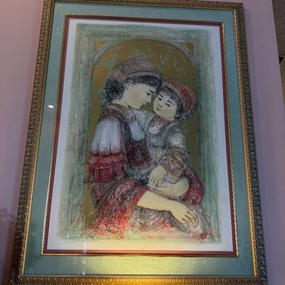 Edna Hibel signed lithograph depicting a mother holding a child, presented in a ornate gold frame with double matting.